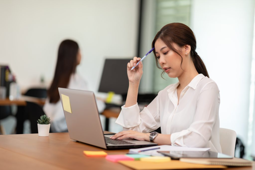 Portrait of Young business woman working with laptop thinking