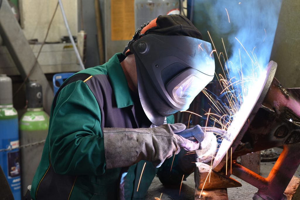 Welder in protective clothing at the workplace in an industrial company in steel construction